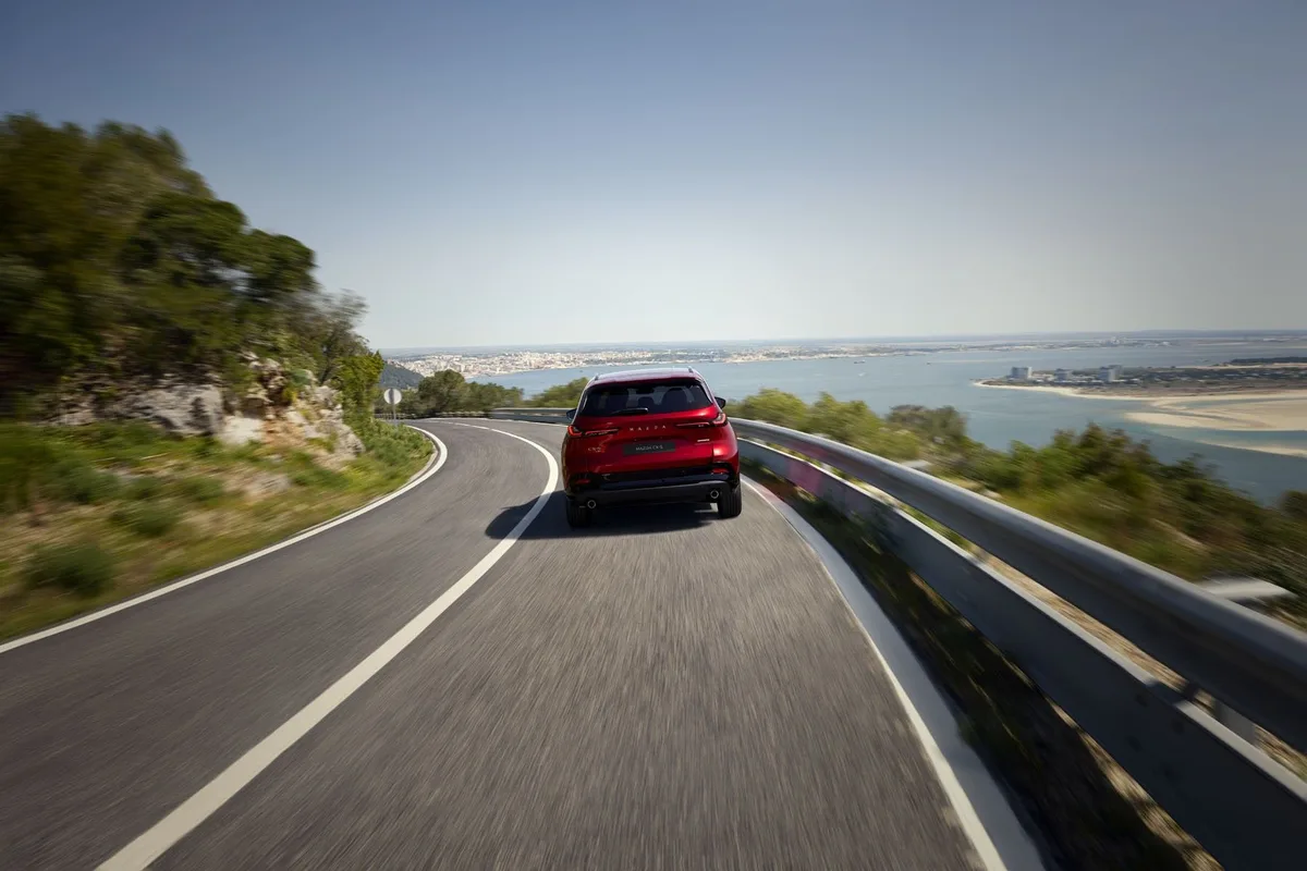 Mazda CX-5 in red driving on a coastal road, rear view