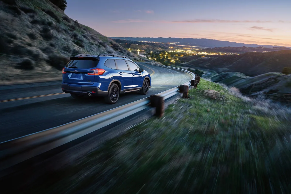 Subaru Ascent in blue on a mountain road at dusk, rear three-quarter view